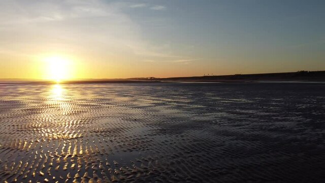 A fast swoop toward the sun across one of the south coasts most beautiful beaches. A burning sunset with hardly any people around.