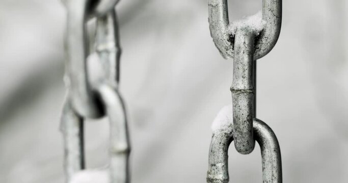 A snowy metal chain hangs on a wintery day.