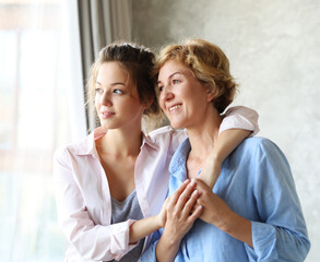 Happy senior mother embracing adult daughter laughing together