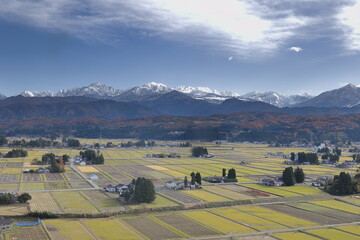 日本にある雪の積もる山と田園の風景