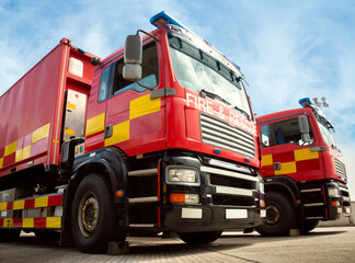 Two red fire truck emergency vehicles. The fire engines carry ladders, firefighting apparatus and...