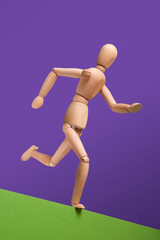 Wooden man fast run forward and ready to jump across precipice on green and purple background. Overcome difficulties.
