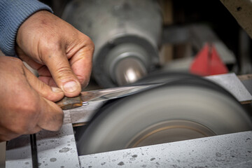 Isolated close up of chef knife sharpening, honing and stropping process by  a skilled craftsman. Vintage old school craftsman at work in grange shop showing true professional skills.