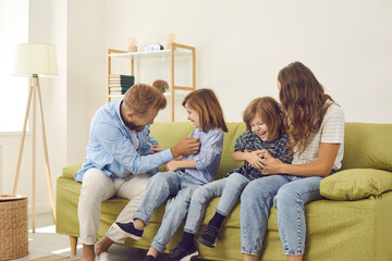 Happy family having fun on sofa at home. Cheerful young European Caucasian mother, father and two...