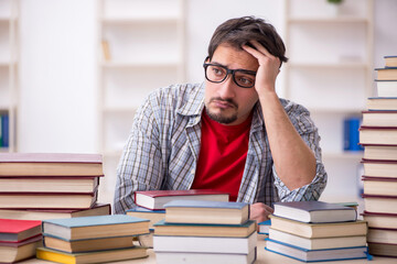 Young male student and too many books in the classroom