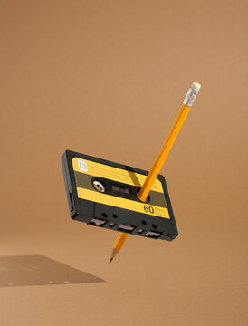 Audio cassette and pencil to rewind the magnetic tape float in the air. Minimalistic retro composition, cool 80s and fantastic music.