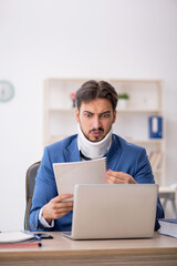 Young neck injured male employee sitting in the office