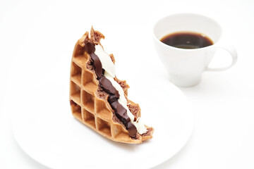 Sweet waffles chocolate sandwich dark and white chocolate recipes on white plate, blurred a cup of hot coffee