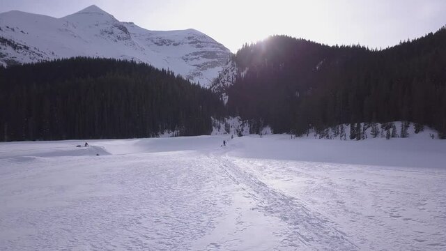 Expedition skiers cross half frozen river at foot of Rocky Mountains