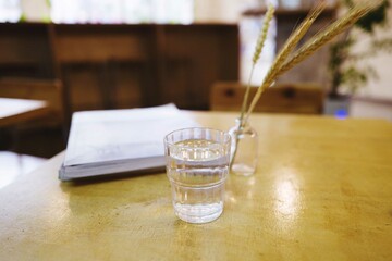 Glass of water on the wooden table with the magazines