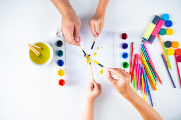 Desk of an artist hands with drawing painting colorful paints and pencil crayons on white background. Artist painting, drawing art. Top view.