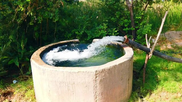 Water from a well filled a pond for irrigation,Pump pipe water flow equipment agriculture,Water from a well filled a pond for irrigation,farming concept