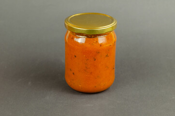 Sea buckthorn jam in a glass jar with a lid on a gray background