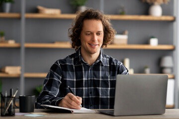 Successful Millennial Man At Laptop Taking Notes Sitting In Office