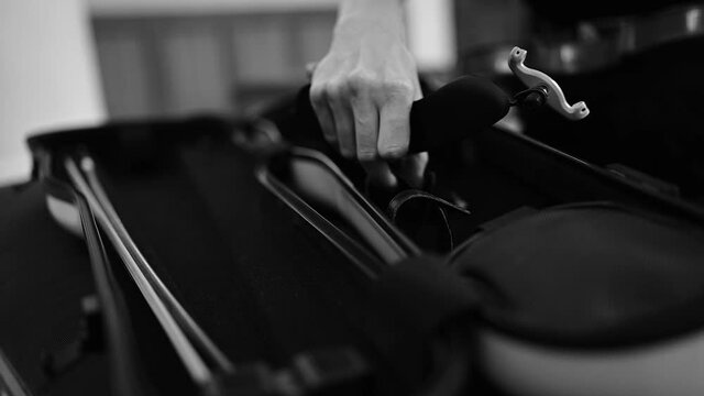 Musician packing violin into special case for transporting