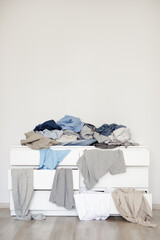 housework concept - chest of drawers with pile of dirty laundry