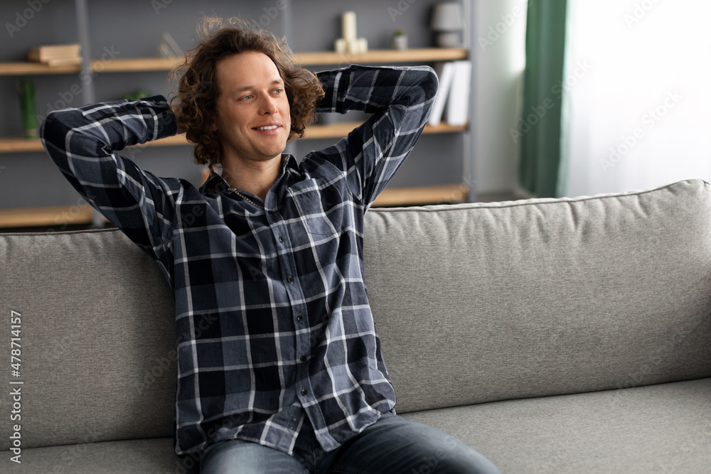 Poster happy man relaxing sitting on sofa and smiling at home