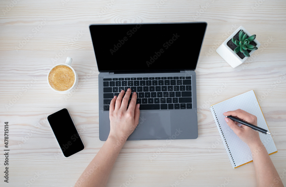 Poster office workspace. unrecognizable businesswoman working at laptop and writing notes in notebook, top 