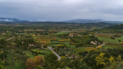 Beautiful panoramic view of Luberon valley near village Gordes, Frence in Provence region in autumn with colorful trees and vineyards on cloudy day.