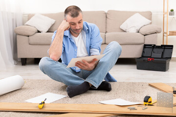 Puzzled Man Reading Furniture Assembly Manual Installing Shelf At Home