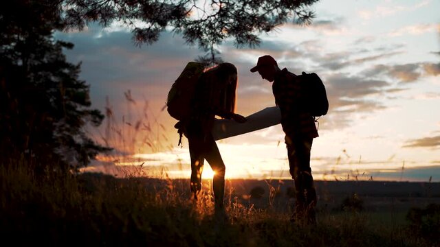 Family tourism with map in forest. Team orienteering in forest. Family travel with map. Teamwork concept. Team of tourists in a forest park with a map. Tourists hiking. Family travel in forest park
