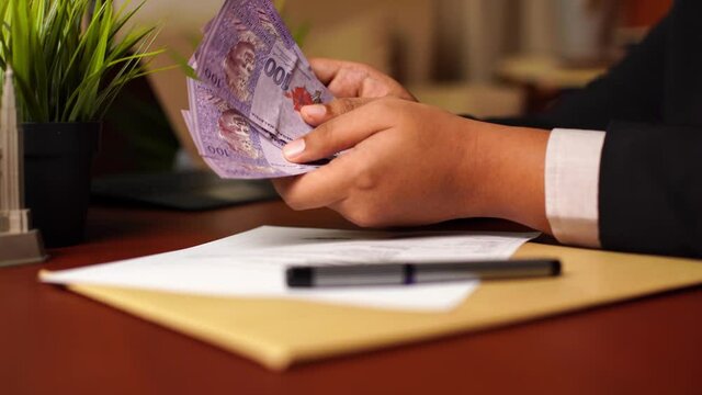 Orbital shot of Businessman or CEO or Politician hands showing and counting bribe money after signing document or contract on the office desk. Venality, bribe, corruption concept.