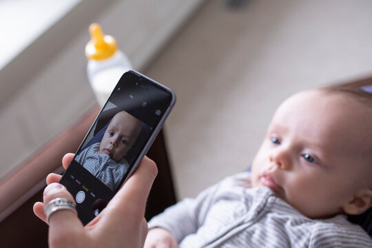 Father photographing baby son on lap camera phone