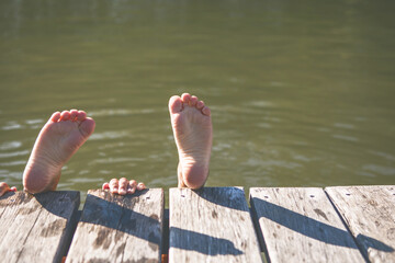 Children's feet against the river. Summer background 