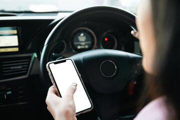 Empty mockup smartphone screen with clipping path. Asian young businesswoman using a smartphone while driving a car, careless woman driver using a phone while driving a car.