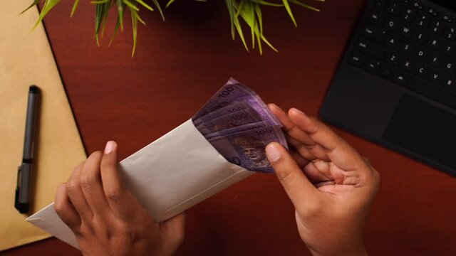 Sliding shot of Businessman or CEO or Politician hands opening an envelope and showing bribe money on the office desk. Venality, bribe, corruption concept.