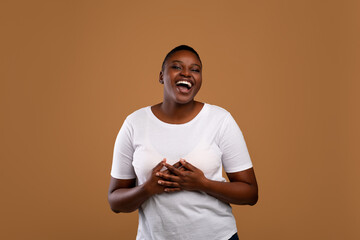 Portrait of casual young black woman laughing, brown wall