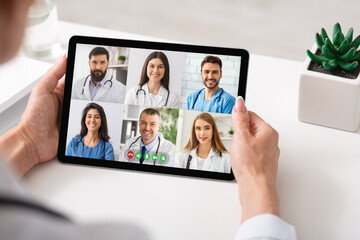 Fototapeta na wymiar Physician Making Group Video Call With Colleagues Using Tablet Indoor
