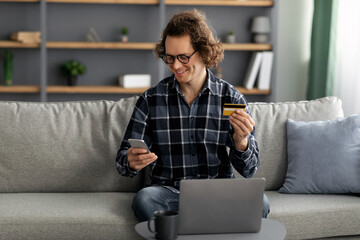 Long-Haired Man Using Credit Card And Phone Shopping Online Indoor