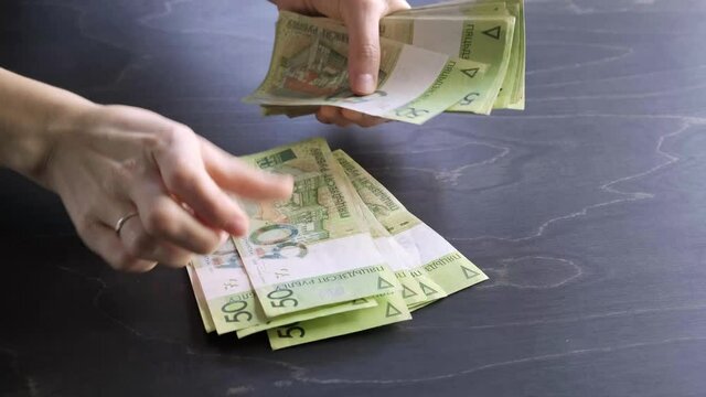 4k. Close-up view of counting stack of belarusian 50 ruble paper money. Hands hold and count a lot of cash. Saving. National currency of Belarus. Credit liabilities. Profit. Big debt. Taxes payment.