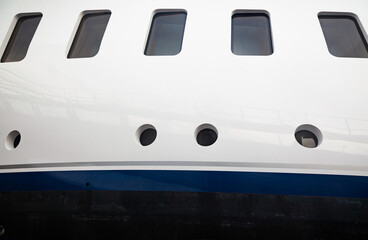 Portholes on the hull of a luxury yacht, above the waterline, side view.