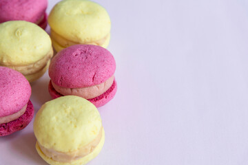 Close-up view of group of colourful (pink and yellow) french macarons lying on pink background. Pastry-shop. Copy space for your text. Confectionery theme.