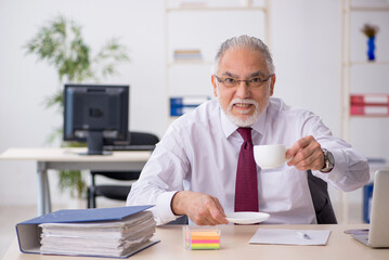 Obraz premium Old male employee drinking coffee during break