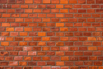Red brick wall texture grunge background with regular pattern. Concrete fence with orange tiles creating urban backdrop. Strong constructing material for outdoor use.