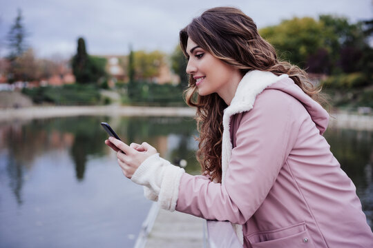 Young woman using mobile phone leaning on railing