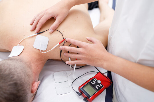 Physical therapist applying electrodes on athlete's neck