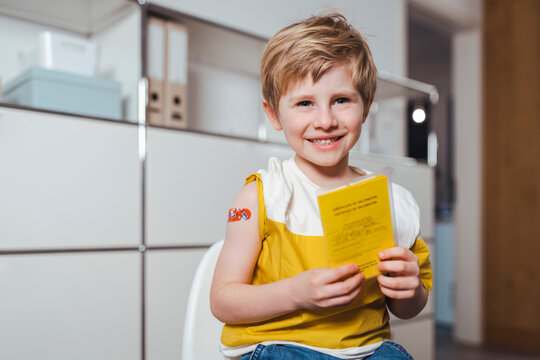 Happy boy holding immunization certificate at center