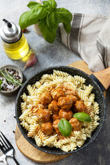 Italian  kitchen. Italian fusilli pasta with meat balls in tomato sauce and basil on grey stone background.
