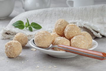 Naklejka premium Close-up view of healthy raw paleo energy coconut balls in white plate. Selective focus.
