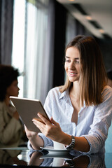 Happy woman manager holding tablet and working