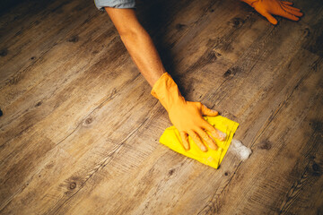 arm from young man clean the floor with yellow cloth