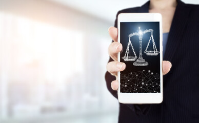 Justice and law concept. Legal advice. Hand hold white smartphone with digital hologram Labor Law sign on light blurred background. Justice law, attorney scale weight court, authority concept.