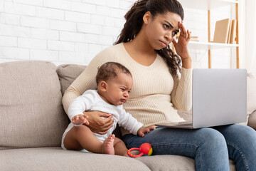 African Mother Trying Work On Computer While Infant Screaming Indoor