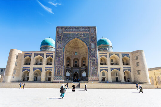 Believers and tourists near the Miri Arab Madrasah in Bukhara on a sunny day, Uzbekistan