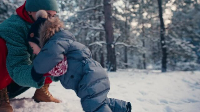 Mother learning her little baby his first steps in the snow forest. High quality 4k footage