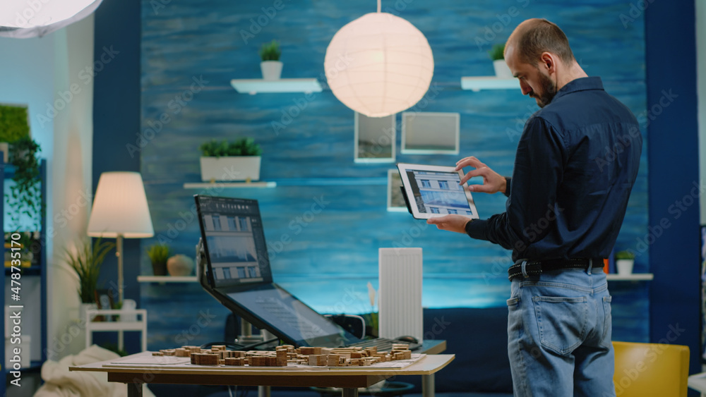 Poster architect looking at tablet with building model for development. man engineer holding gadget and ana